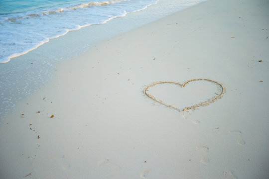 Heart painted in white sand on a tropical beach