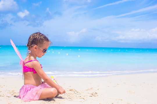 Adorable little girl with wings like butterfly on beach vacation