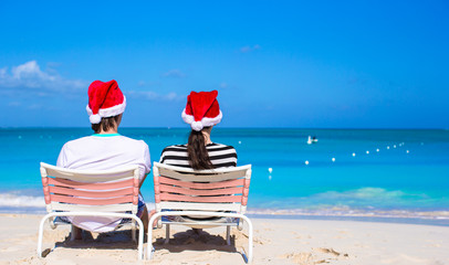 Young happy couple in red Santa hats on tropical beach