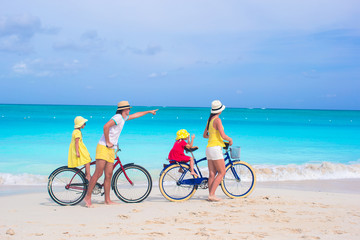 Fototapeta premium Young happy family riding bicycles duting beach vacation