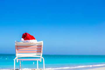 Closeup red Santa hat on chair longue at tropical beach