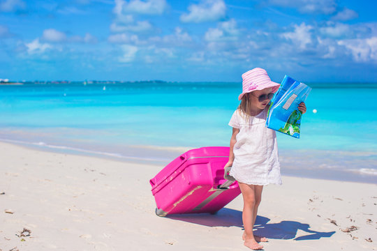 Little adorable girl with big suitcase on tropical vacation