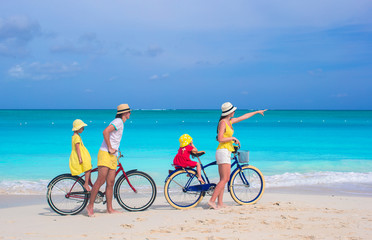 Fototapeta premium Young family riding bicycles on tropical beach