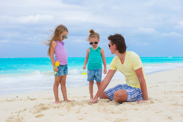 Fototapeta na wymiar Adorable little girls and happy dad on tropical white beach