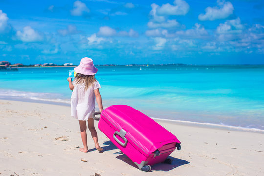 Little adorable girl with big suitcase on tropical vacation