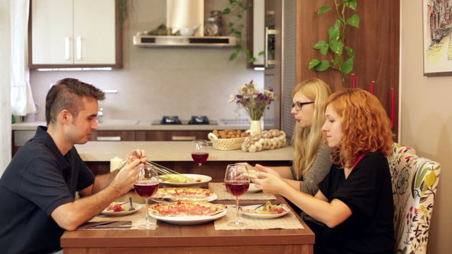 Group of friends eating pizza in dining room at home.