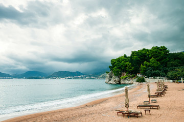 luxury beach resort with sunbeds and umbrellas with rainy sky