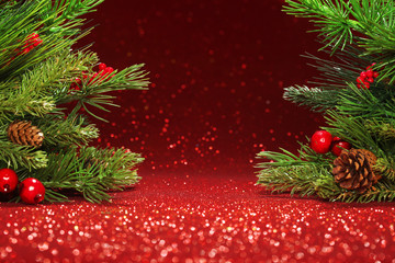 Christmas tree branches on glittering red background