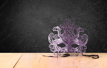 Filigree Mysterious Venetian masquerade mask on wooden table and