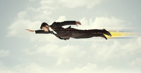 Happy business man flying fast on the sky between clouds
