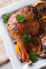 fried duck leg with oranges on a white plate vertical top view