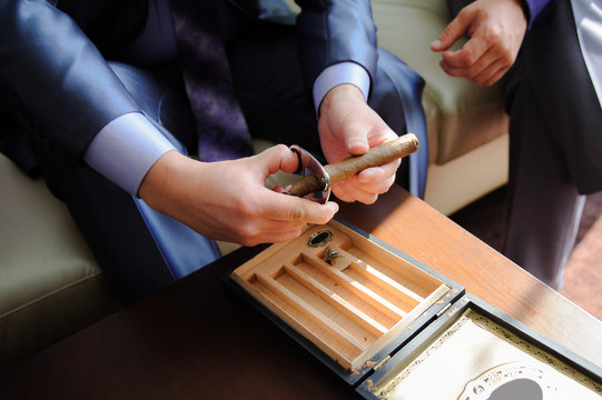 Male hands cutting cigar