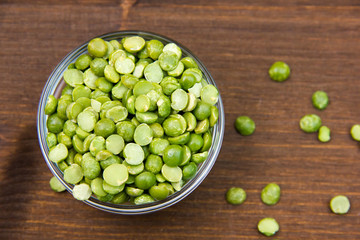 Dried peas in bowl on wooden table seen from above