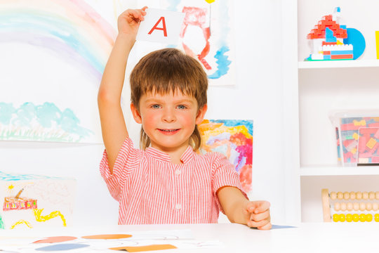 Boy showing letter flashcard in reading class