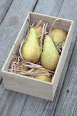 Wooden box of fresh pears on timber planks.