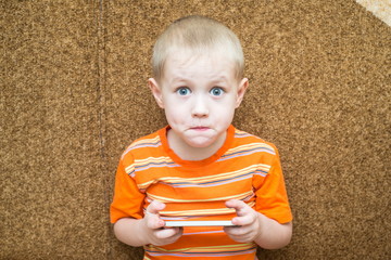 Surprised boy holding a smartphone in the hands and sitting on