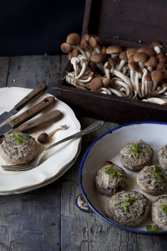 stuffed mushrooms on wooden table with plate and raw mushrooms