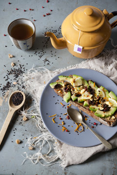 wholemeal vegan toast with avocado slices and seeds with teapot