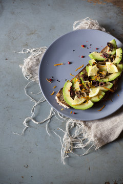 wholemeal vegan toast with avocado slices and seeds on plate