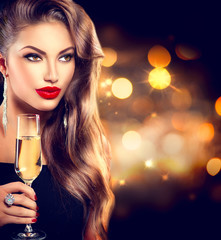 Sexy girl with glass of champagne over holiday background