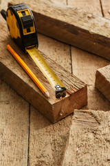 Measure tape and pencil on wooden palnks