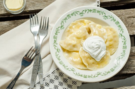 Vareniki - traditional russian dumplings with potatoes in vintage plate on wooden background