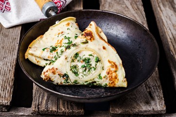 Ukrainian pancakes with meat, greens and onion in iron plate on wooden vintage background