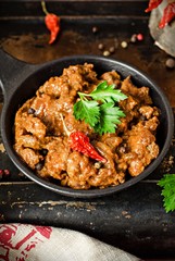 Stewed beef liver with tomatoes sauce in iron pot on iron dark background
