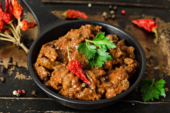 Stewed beef liver with tomatoes sauce in iron pot on iron dark background