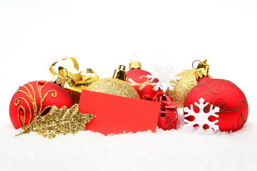 Golden,red christmas decoration on snow with wishes card