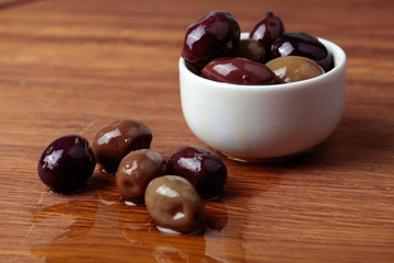 different olives in white bowl on wooden board