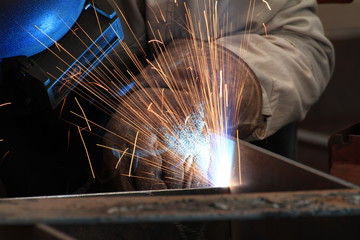 MIG welder welding steel part with all safety equipment