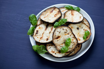 Grilled aubergine slices over dark blue wooden surface, close-up