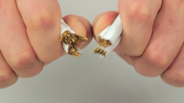 hands tearing three cigarettes closeup