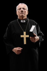 Mature male priest holding a holy bible