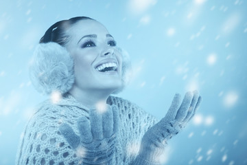 Woman in winter clothes catching snowflakes