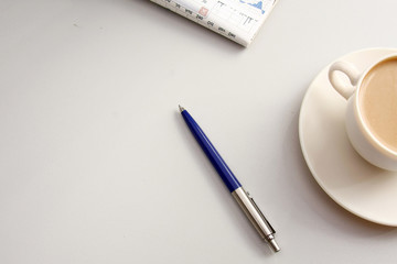 A cup of coffee and a pen on the table, closeup