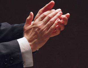 Male hands clapping on black, side-view