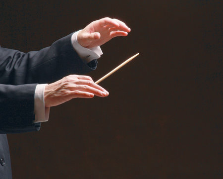 Concert conductor's hands with a baton, isolated on a black