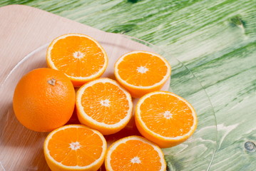 sliced ripe appetizing orange on a cutting board on a green tabl