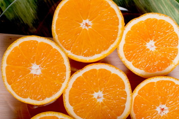 sliced ripe appetizing orange on a cutting board on a green tabl