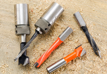 Drill bits and the scale on a wooden background