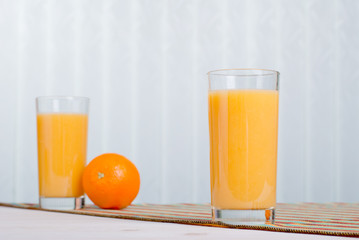 Orange fresh juice beside delicious ripe oranges on the table