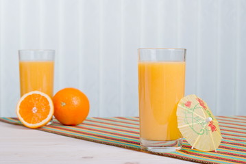 Orange fresh juice beside delicious ripe oranges on the table