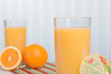 Orange fresh juice beside delicious ripe oranges on the table