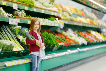 Little girl choosing a leek in a store