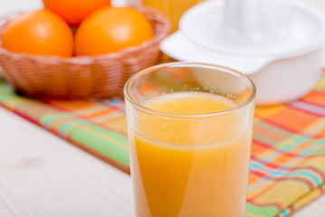 Orange fresh juice beside delicious ripe oranges on the table