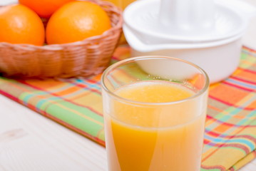 Orange fresh juice beside delicious ripe oranges on the table