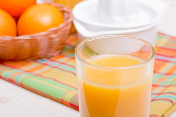 Orange fresh juice beside delicious ripe oranges on the table