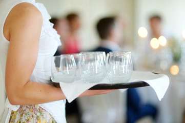 Waitress holding a dish of glasses